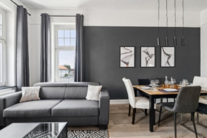 Gemütliches Wohnzimmer der Ferienwohnung in Hameln mit grauer Couch, modernem Essbereich und stilvoller Wandgestaltung