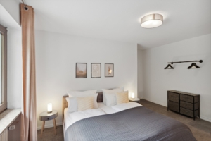 Modernes Schlafzimmer mit Doppelbett, minimalistischer Einrichtung und Wandbildern in der Ferienwohnung in Hameln